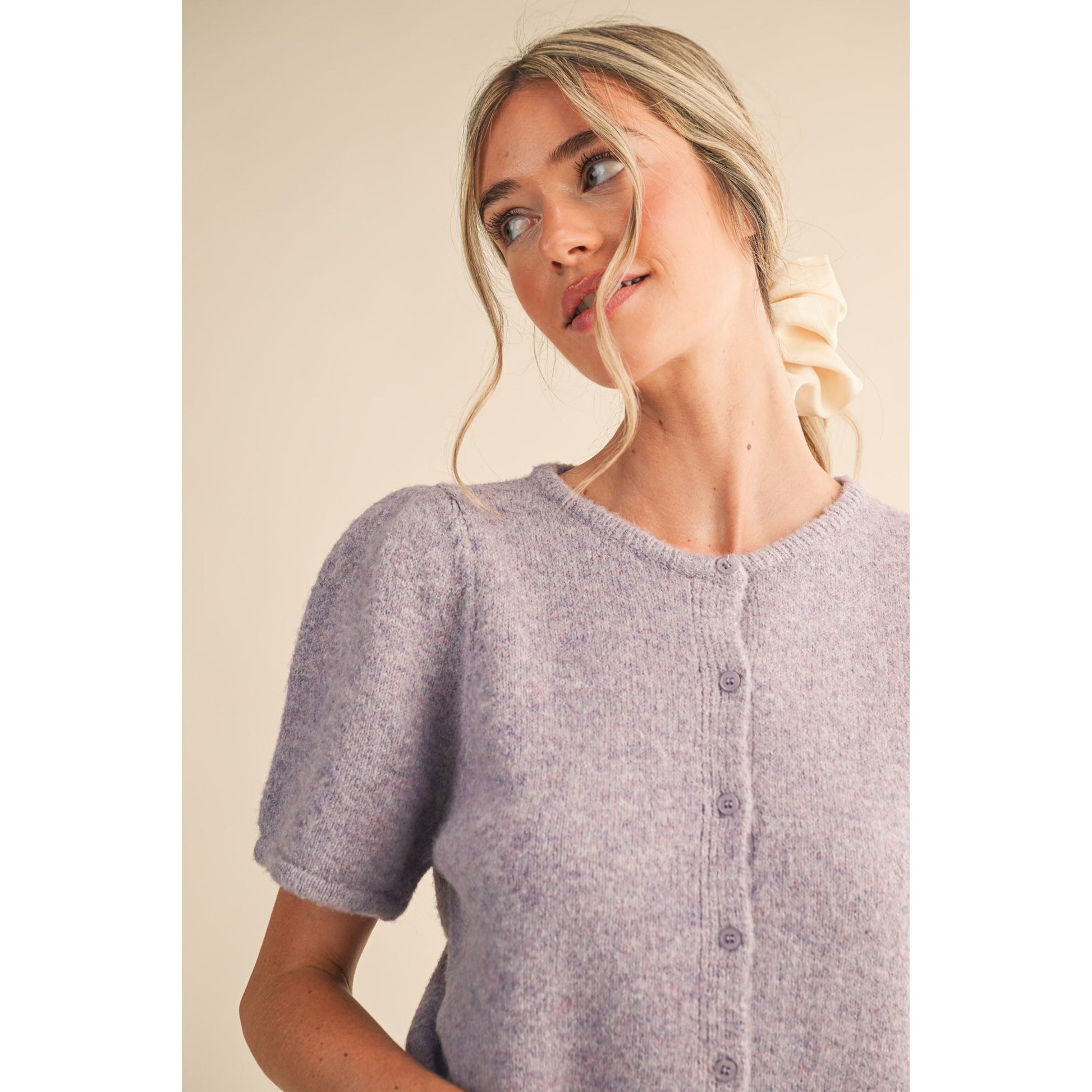 Woman wearing a light purple knitted cardigan against a plain background