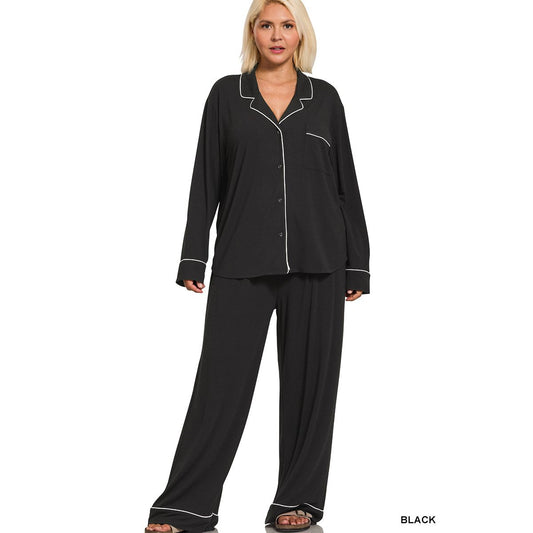Woman wearing a black long sleeve and pants pajama set with white piping on a white background
