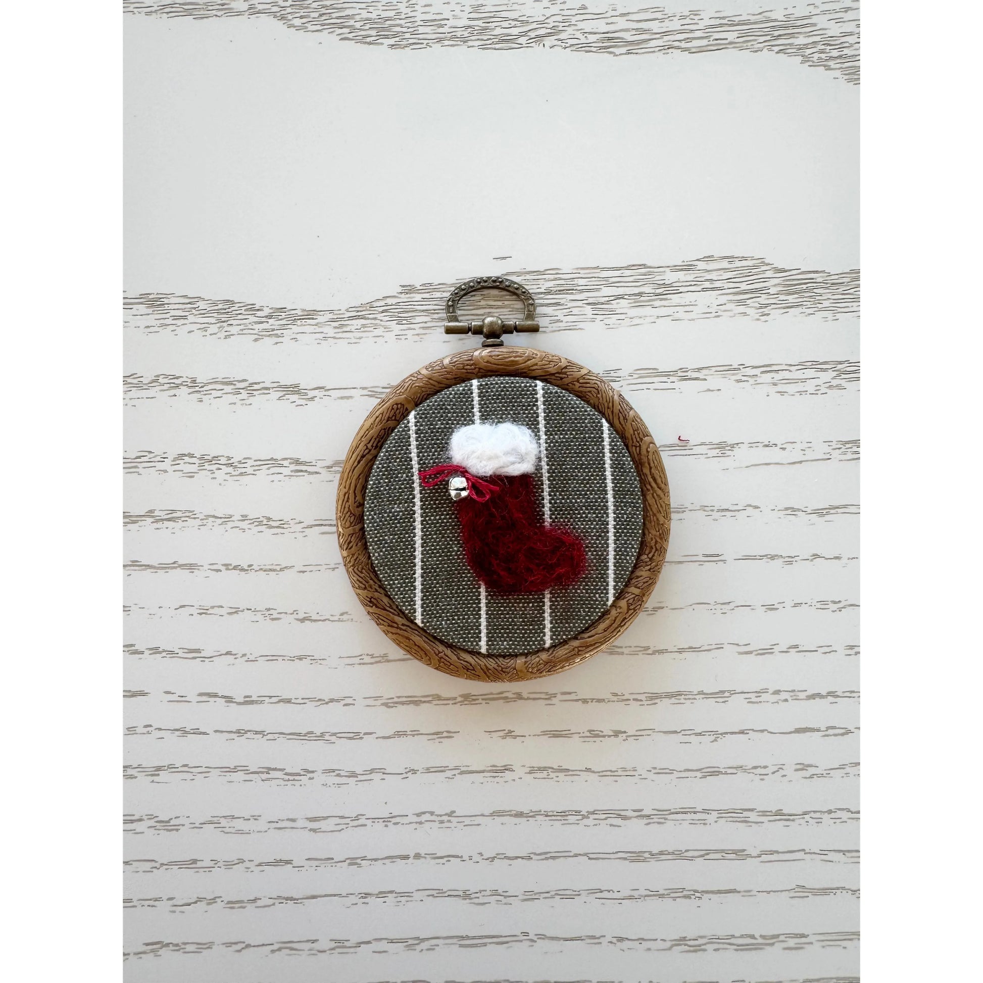 Embroidery hoop with a red stocking and white snowman on a striped background
