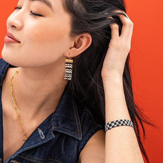 Woman wearing gold earrings and necklace with a red background