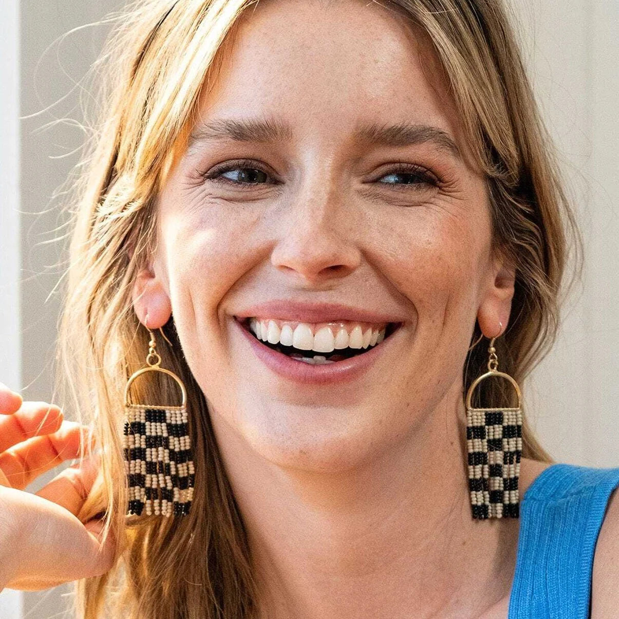 Woman wearing checkered earrings with a blurred background