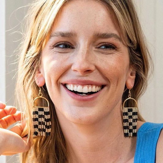Woman wearing checkered earrings with a blurred background