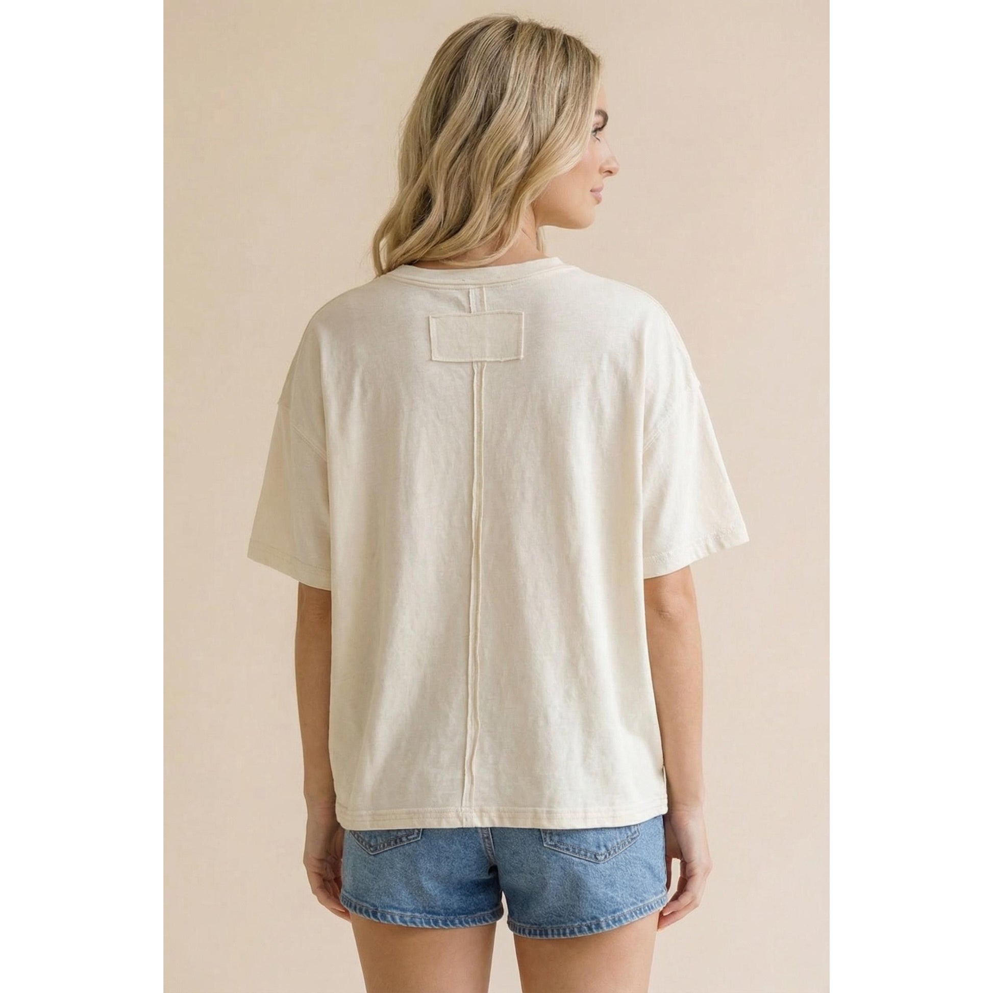 Woman wearing a beige t-shirt with a zipper on a beige background