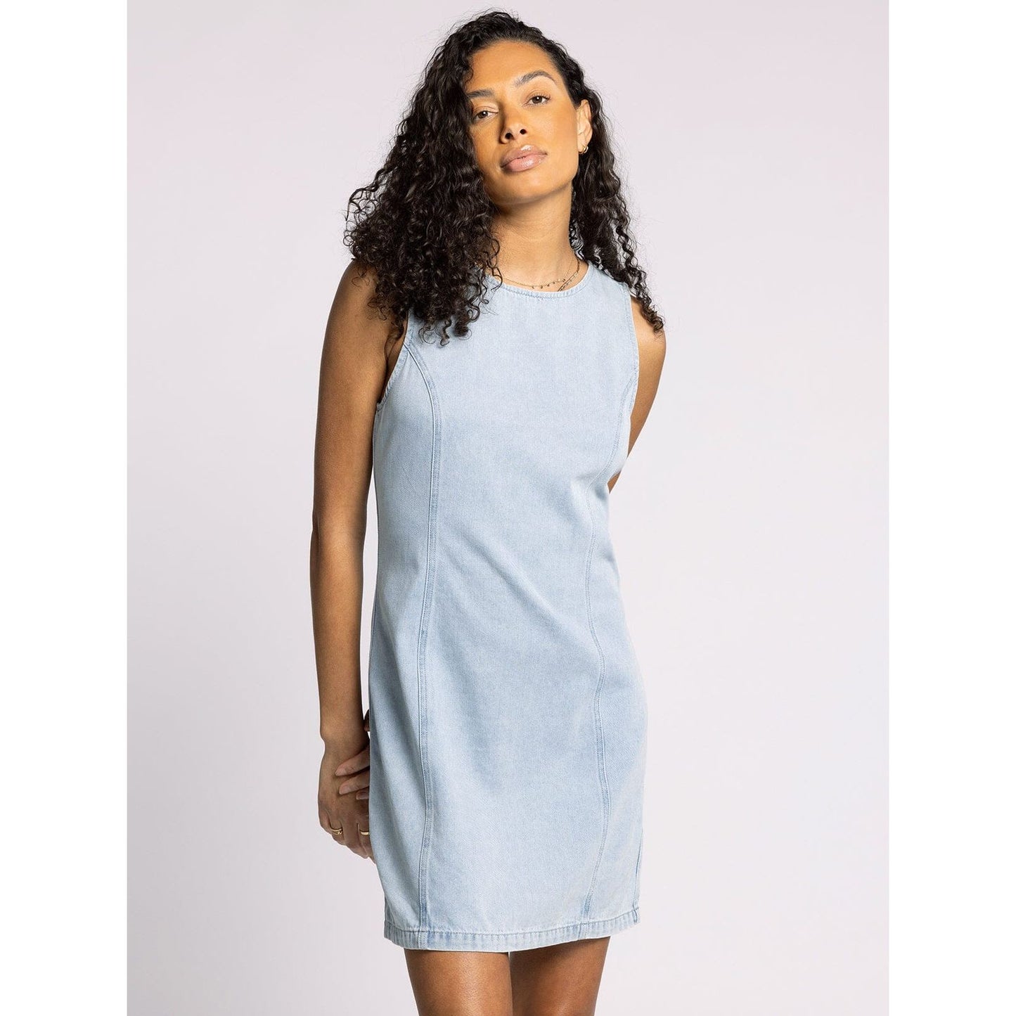 Woman wearing a light blue denim dress against a plain background