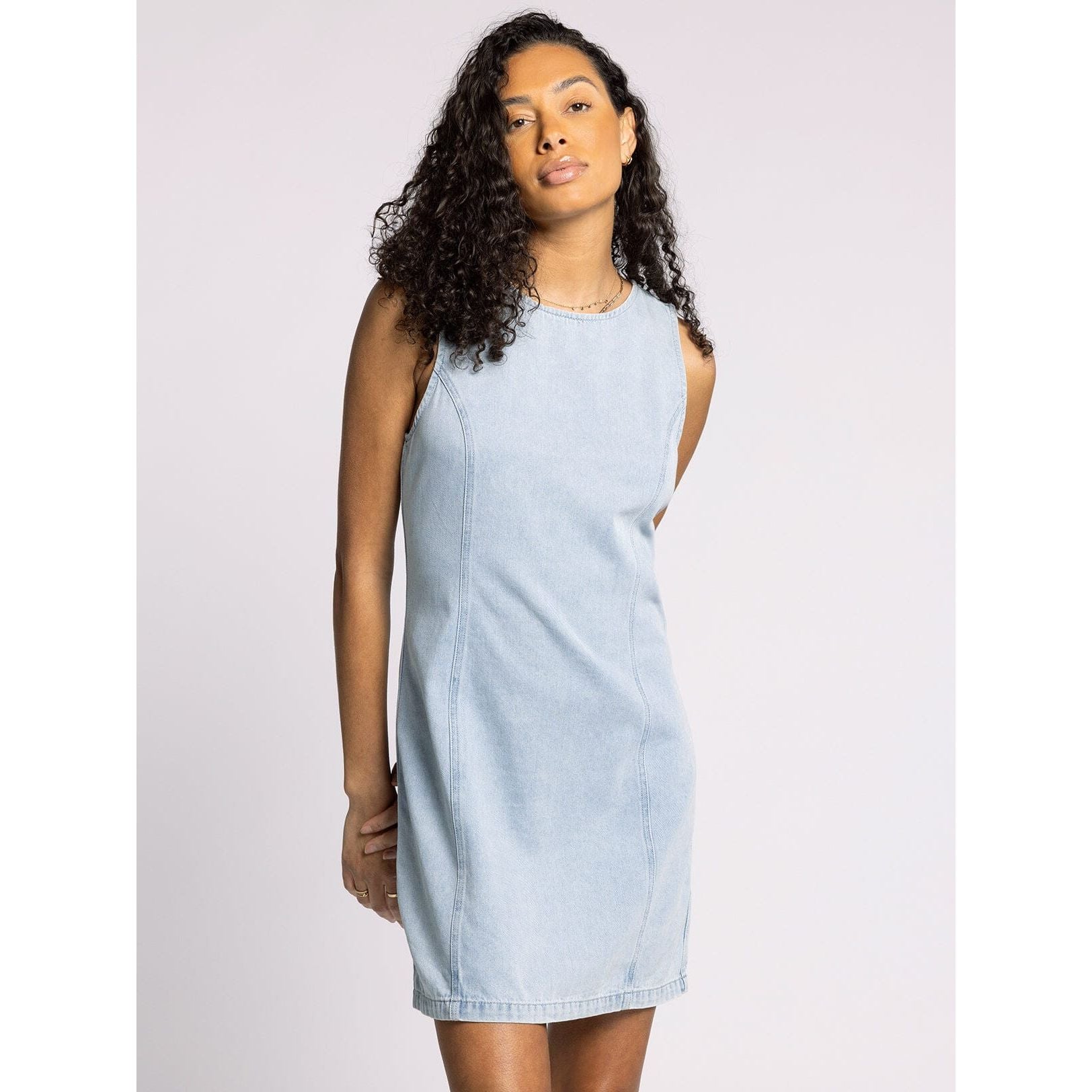 Woman wearing a light blue denim dress against a plain background