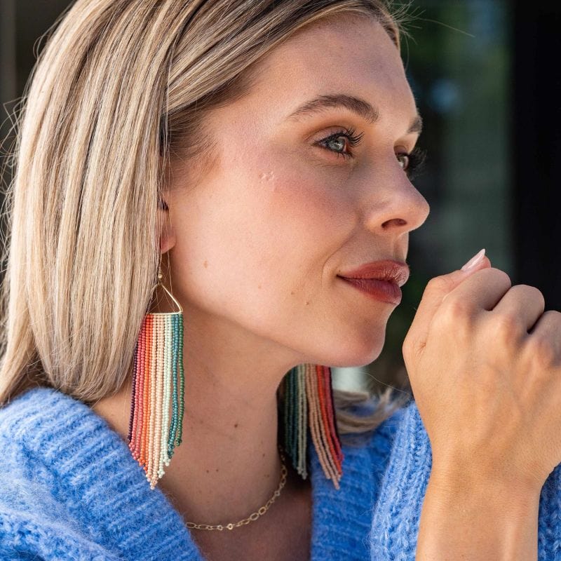 Woman wearing colorful beaded earrings with a blurred background