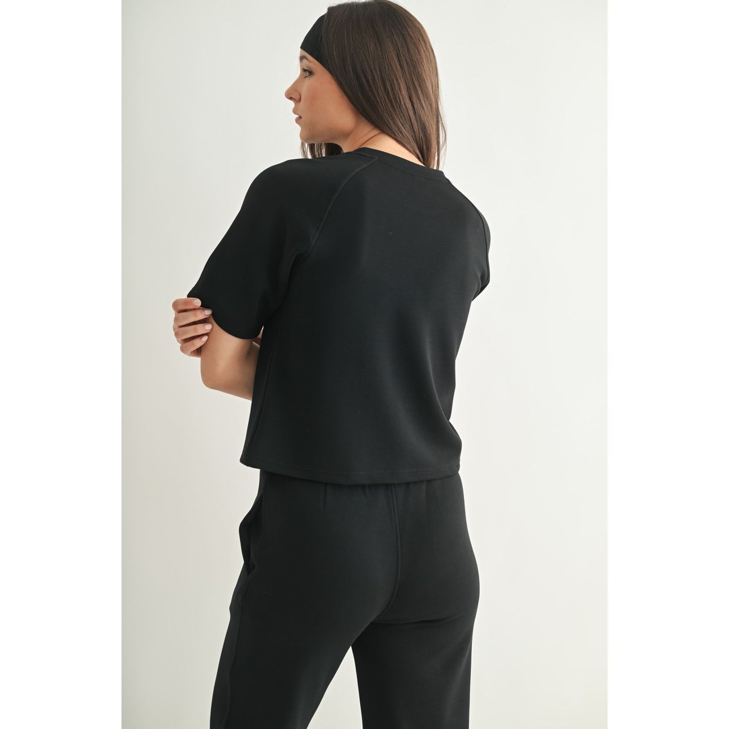 Back view of a woman wearing a black short sleeve shirt on white background