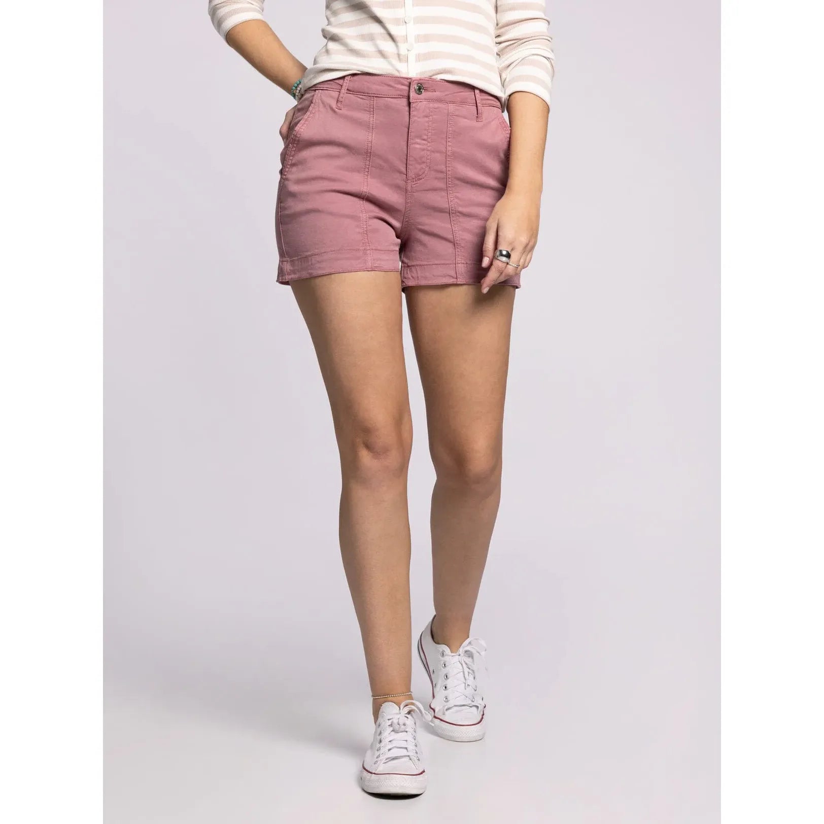 Person wearing pink shorts and white sneakers on a plain background